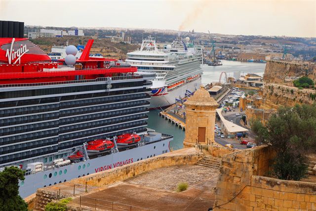 Cruise ships berthed in Valletta Grand Harbour below the city bastions and stone watchtower, Malta