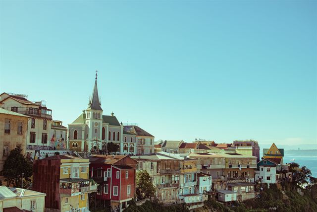 Colorful hillside houses and a church spire on a Valparaiso hill above the sea