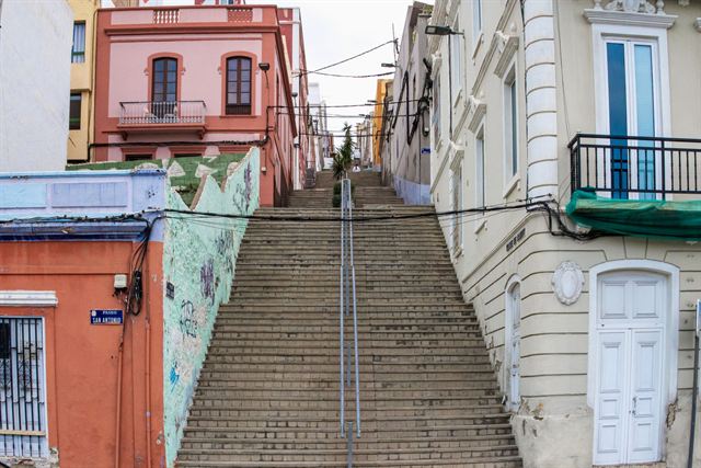 Steep stone staircase between colorful pastel buildings and graffiti walls in Valparaiso