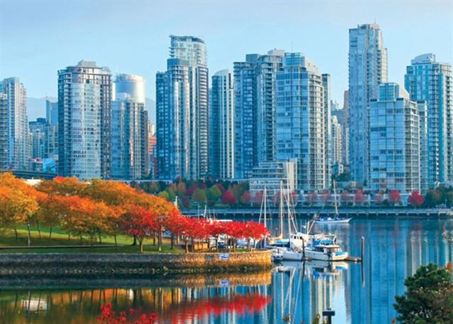 Glass residential towers above a marina and autumn-colored trees on the waterfront