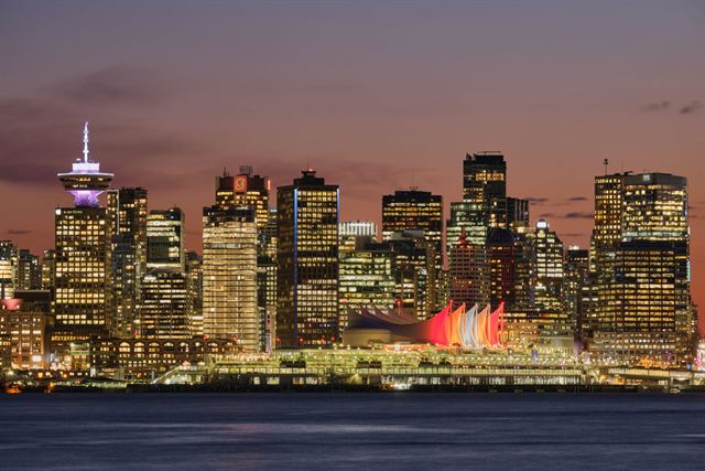 Downtown Vancouver skyline lit up at twilight with Harbour Centre tower and Canada Place sails