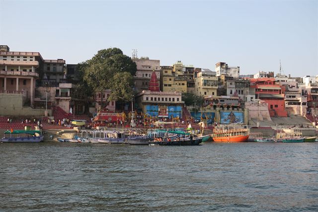 Colorful riverside buildings and stepped ghats of Varanasi seen from the Ganges with moored boats