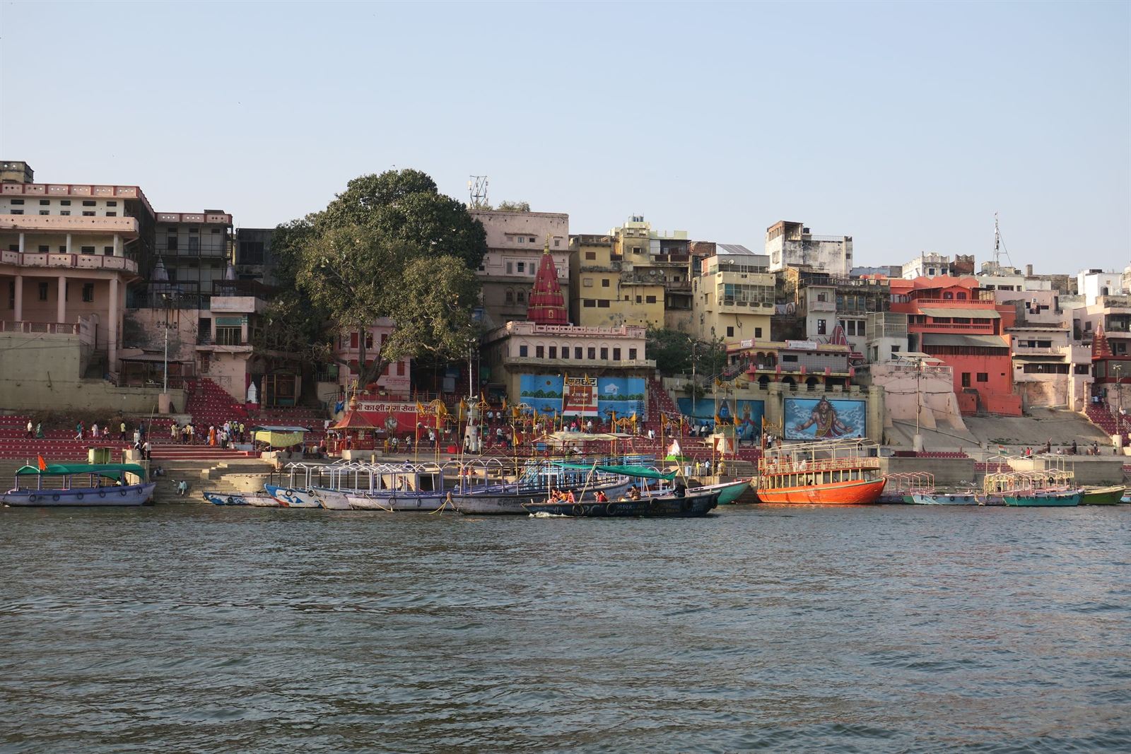 Colorful riverside buildings and stepped ghats of Varanasi seen from the Ganges with moored boats
