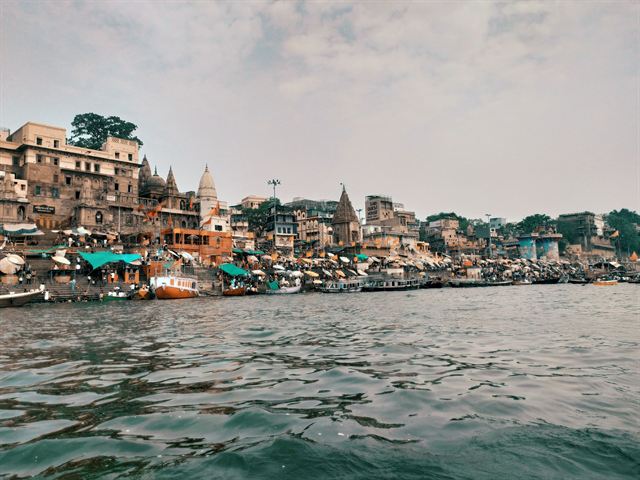 Varanasi's ghats and temples lining the Ganges river with boats along the bank