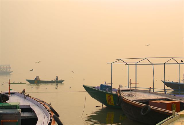 Wooden boats on the misty Ganges at Varanasi in hazy golden morning light