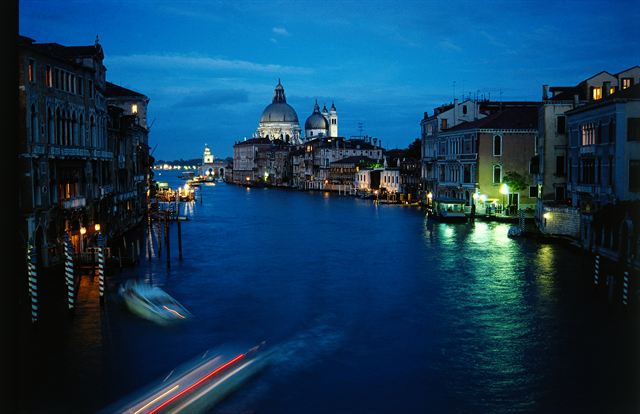 Grand Canal at dusk in Venice with lit palazzi and the dome of Santa Maria della Salute