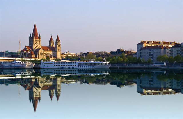St. Francis of Assisi Church and river cruise ships reflected in the Danube at Vienna