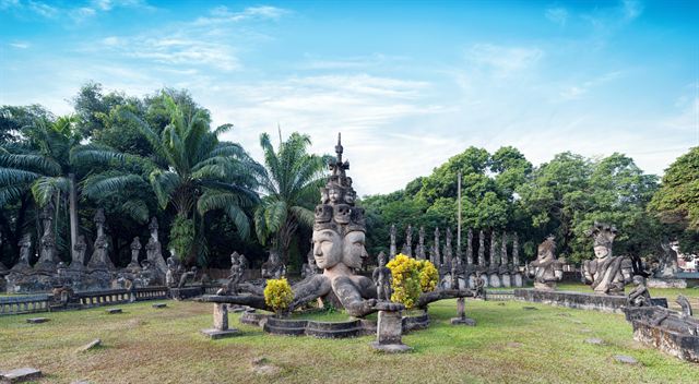 Buddha Park near Vientiane with rows of concrete Buddhist and Hindu sculptures under palms