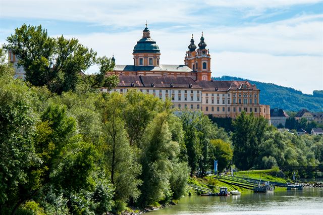 Melk Abbey's twin towers and dome above trees along the Danube
