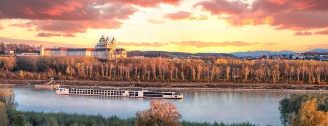 Melk Abbey at sunset with a river cruise ship on the Danube below