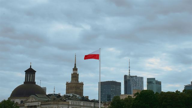 Warsaw skyline with the Palace of Culture and Science spire, a church dome and a Polish flag