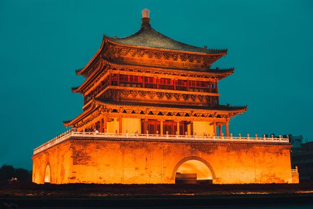 Xi'an Bell Tower, a tiered Ming-dynasty pavilion glowing orange at dusk on its brick base