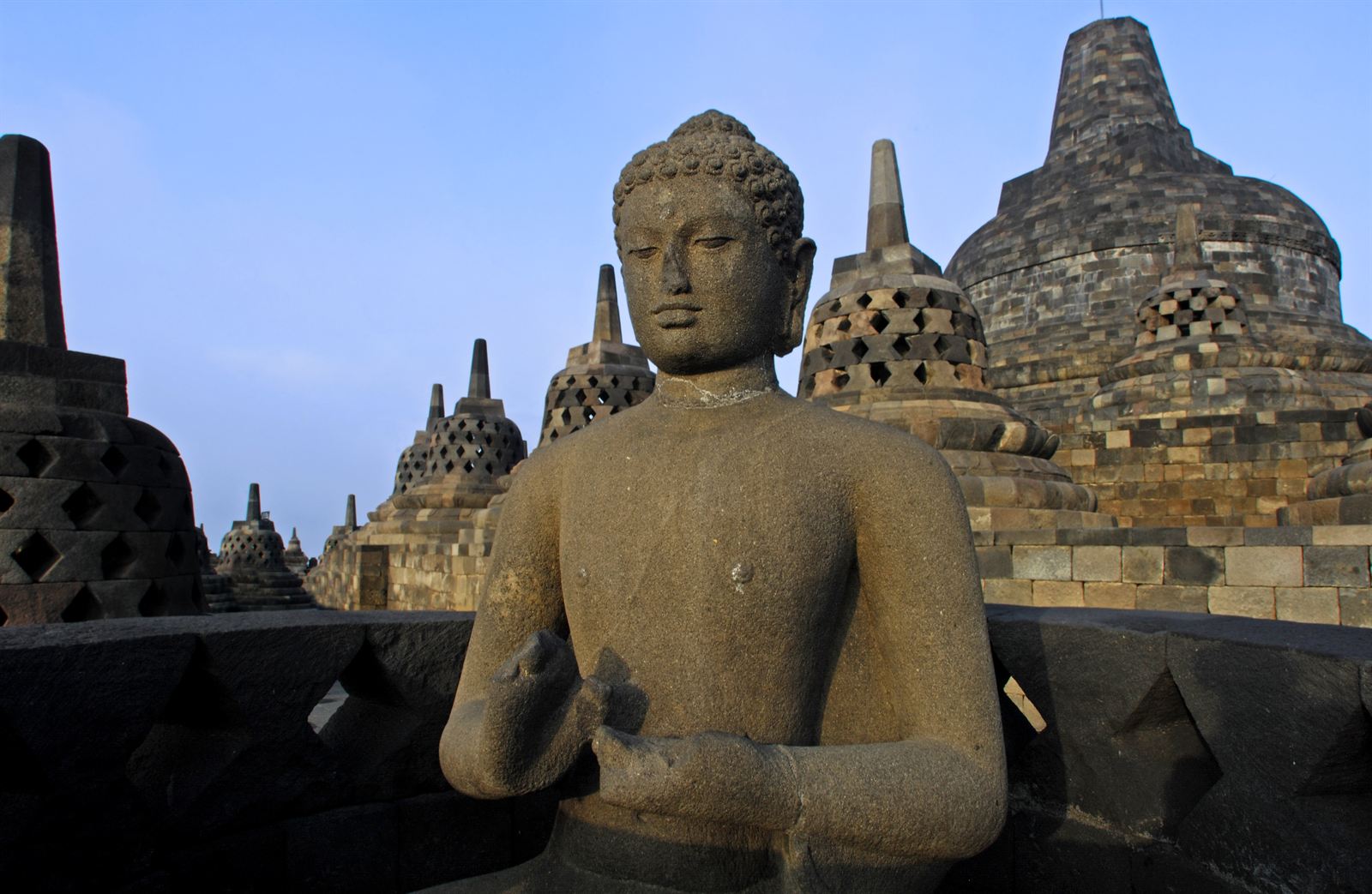 Stone Buddha and bell-shaped stupas on the terraces of Borobudur near Yogyakarta
