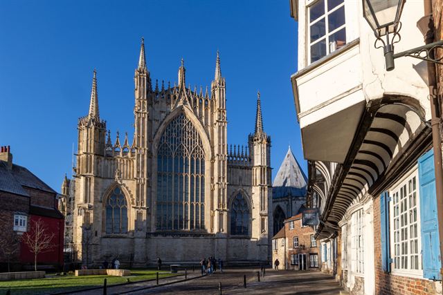 West front of York Minster with its twin Gothic towers seen from a narrow York street